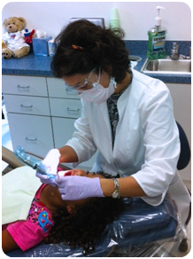 Dr. Churchill performing teeth cleaning on a child.